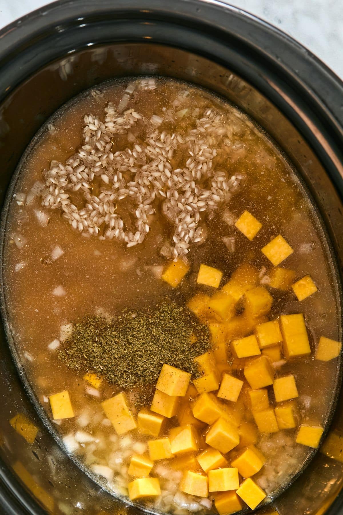 Broth, butternut squash and rubbed sage added to the slow cooker.